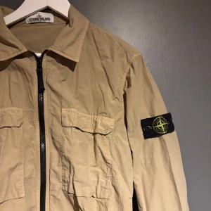 Beige overshirt från Stone Island - Säljer en overshirt/jacka från stone Island. Den är i jätte bra skick. Qr scan finns på jackan. Finns att hämta i Växjö eller fraktas! Passar L och M