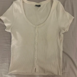 Vit ribbad topp - Säljer en stilren vit ribbad topp med knappar framtill. 