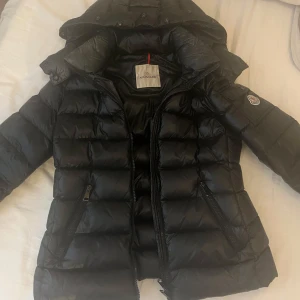 Svart dunjacka från Moncler - Säljer en snygg svart moncler jacka! den är i storlek 1, man får även med fluff till luvan vilket man ser på sista bilden! skriv för fler bilder och tveka it att höra av sig😇 (köptes för 5500 här på plick för unge 2 månader sedan)