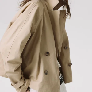 Beige trenchcoat - Snygg beige trenchcoat med dubbelknäppning och klassisk krage, croppad. Jackan har en lös passform och är perfekt för vår och höst. Använd ca 3 ggr