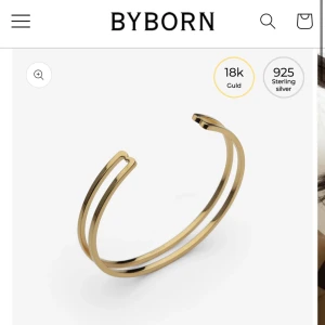 Guldarmband från Byborn - Elegant armband i 18k guld från Byborn. Designen är minimalistisk med en öppen form och dubbla band som ger en modern touch. Perfekt för att lägga till en lyxig känsla till din stil. Ny pris - 1000kr