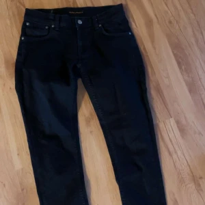 Nudie jeans  - Snygga svarta jeansbyxor med en klassisk femficksdesign. De har en knapp och dragkedja framtill. Perfekta för en stilren look. Märke Nudie storlek W30