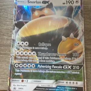 Snorlax GX Pokémonkort - Säljer ett Snorlax GX Pokémonkort med 190 HP. Kortet har attacker som Collapse, Thunderous Snore och Pulverizing Pancake GX. Perfekt för samlare eller spelare som vill förstärka sin kortlek med en kraftfull Pokémon.