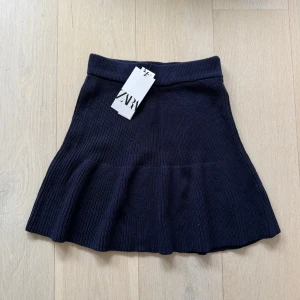 Mörkblå stickad kjol från Zara - Helt ny, snygg mörkblå stickad kjol från Zara med en volangdetalj längst ner. Kjolen har en ribbad struktur och en bekväm passform som passar perfekt till olika tillfällen😍🌟