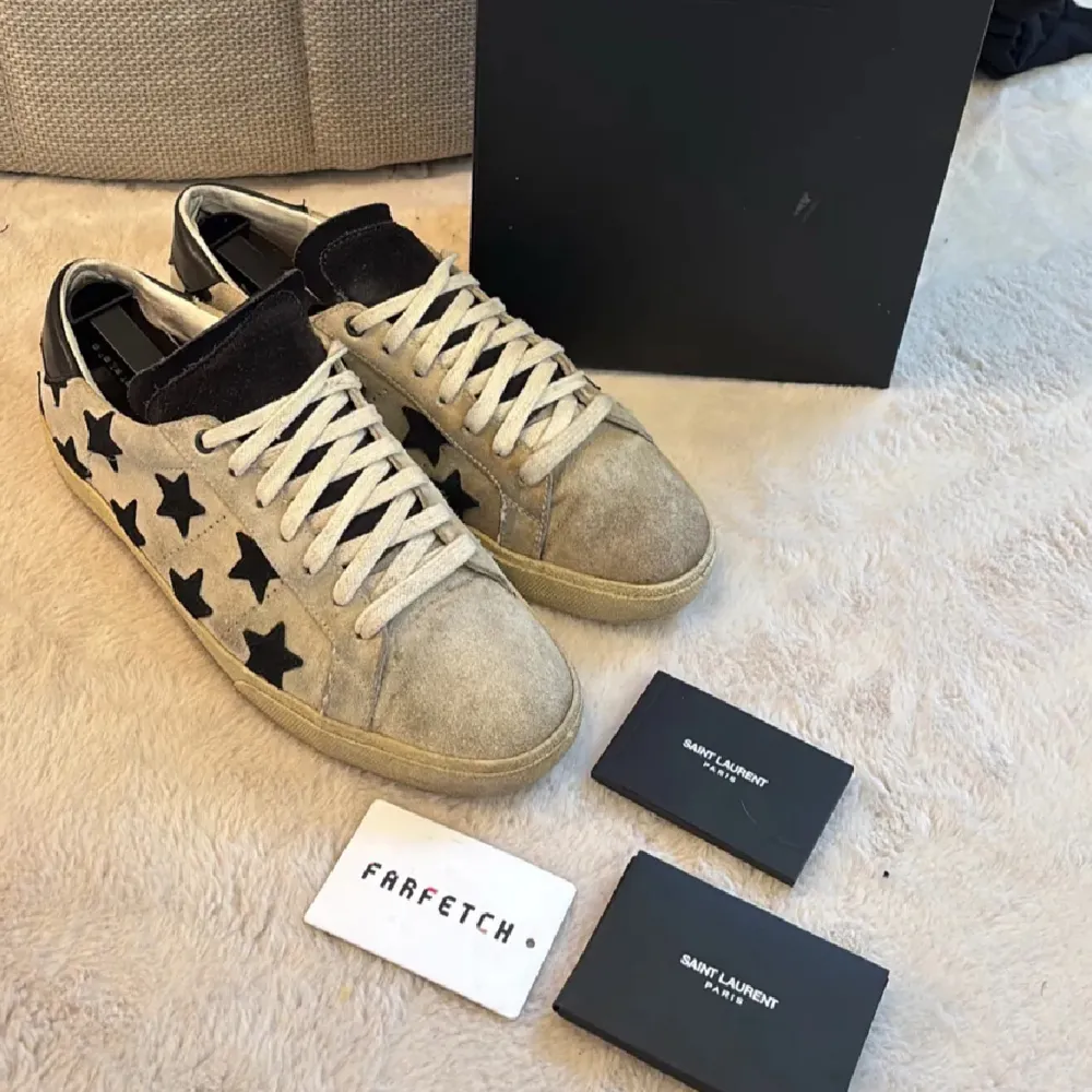 Snygga sneakers från Saint Laurent i beige mocka med svarta stjärnor. Skorna har snörning och en klassisk design som passar perfekt för en trendig look. Riktigt snygga och perfekta nu till sommaren! Skulle själv säga att det är den absolut fetaste modellen på ysl skor🌟. Kengät.