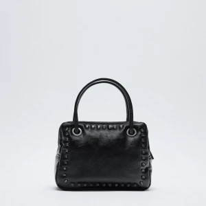 Väska med nitar - Handväska med nitar från zara. Långa bandet följer med. Köpt på plick/vinted och sparsamt använd av mig och säljaren. Ena öglan har en lagning men inget som syns eller stör annars i toppskick.