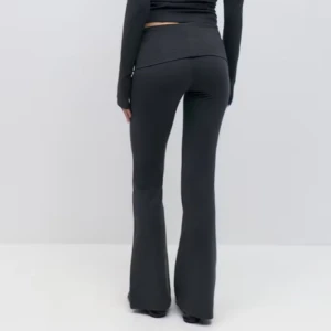 Grå yoga pants med sett - Snygga grå bootcut byxor med  tillhörande tröja med öppen rygg. Perfekta för en stilren look. Byxorna har en tight passform upptill och vidgar sig nedtill för en klassisk bootcut-stil. Byxorna xs och tröjan s, använt ett fåtal gånger. 