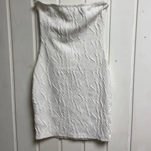 Vit axelbandslös klänning - Snygg vit figursydd klänning med ett unikt texturerat mönster🤍