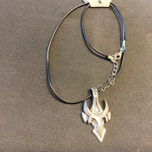 Halsband med unika hängen - Säljer fyra olika halsband med unika hängen. Två halsband har silverfärgade hängen med futuristisk design på svart snöre. Ett halsband har ett guldfärgat ankare på en tunn kedja. Det sista halsbandet har ett silverfärgat ankare på en kedja. Perfekt för att ge din stil en personlig touch. 125kr/st , helt ny 