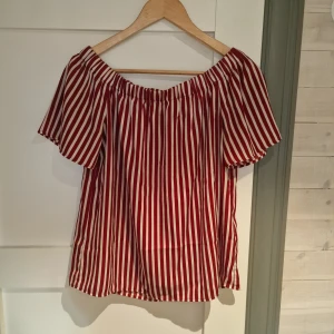 Röd- och vitrandig offshoulder topp från H&M - Säljer en snygg röd- och vitrandig offshoulder topp från H&M. Toppen har korta ärmar och en luftig passform, perfekt för varma dagar. Den elastiska kanten ger en bekväm och stilren look. Passar utmärkt till både jeans och kjol. 🌟