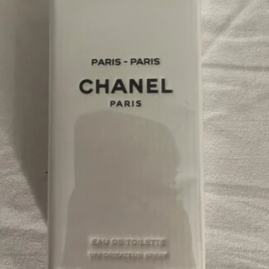 Chanel Paris Eau de Toilette - Elegant och tidlös Eau de Toilette från Chanel, Paris. Förpackningen är stilren och vit med svart text. Perfekt för den som älskar klassiska dofter med en touch av lyx.