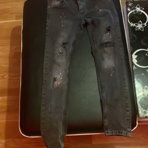 Grå jeans med slitningar från Denim Park - Snygga grå jeans från Denim Park med coola slitningar och färgstänk. De har en slim fit passform som ger en modern look. Perfekta för dig som vill ha en edgy stil.