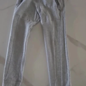 Grå mjukisbyxor från KappAhl - Säljer ett par grå mjukisbyxor från KappAhl. Byxorna har en bekväm passform med elastisk midja och dragkedja vid fickorna. Perfekta för en avslappnad stil.