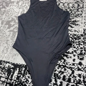 Svart body - Snygg svart body med enkel och stilren design. Tillverkad i ett bekvämt material som sitter bra på kroppen. Helt ny