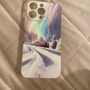 Mobilskal  för  iPhone 14 pro max  - Snyggt mobilskal med ett vackert vinterlandskap och norrsken. Skalet har en bild av ett tåg som kör genom ett snötäckt landskap med färgglada norrsken i bakgrunden. Perfekt för att ge din telefon ett unikt och vintrigt utseende.
