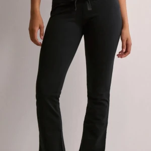 Svarta mjukis byxor från Nelly - Snygga svarta bootcut byxor med snörning i midjan. Perfekta för en stilren look med en bekväm passform. Byxorna har en klassisk design som passar till många olika tillfällen.