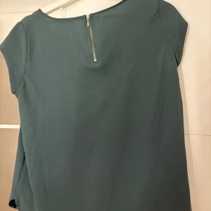 Blågrön topp från ONLY - Snygg blågrön topp från ONLY med korta ärmar och dragkedja i ryggen. Hör av er vid funderingar eller om ni vill ha bilder med hur plagget sitter på mig. Titta gärna in mina andra plagg!