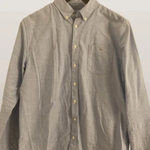 Blå skjorta från GANT - Snygg blå skjorta från GANT med klassisk design. Skjortan har långa ärmar och en bröstficka med broderad logotyp. Perfekt för en stilren look. Pris kan diskuteras!😄