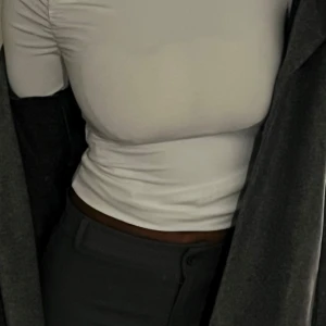 Vit långärmad topp - Säljer en stilren vit långärmad topp med en tight passform. Perfekt för att kombinera med olika outfits. Passar bra till både vardag och speciella tillfällen.