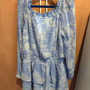 klänning - Söt blå klänning med vita blommor från Kappahl. Klänningen har långa ärmar och en elastisk midja för en bekväm passform. Perfekt för vår och sommar med sitt lätta och luftiga material. Nypris: ca 400kr (använd fåtal gånger)