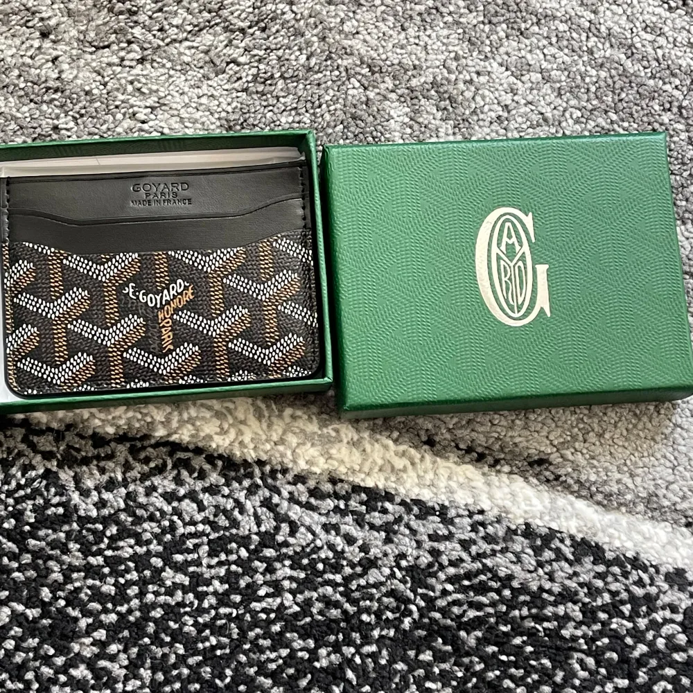 Elegant plånbok från i svart och brunt med det ikoniska mönstret. Plånboken har en stilren design med en insida i gult. Perfekt för att hålla dina kort och kontanter organiserade.. Laukut & Käsilaukut.