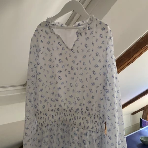 Vit blommig klänning - Säljer en söt vit klänning med blått blommönster från Gina tricot. Klänningen är aldrig använd och i storlek 158-164.💕