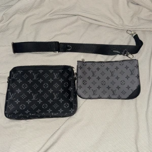 Monogram axelväska i svart och grått - Snygg axelväska med monogrammönster i svart och grått. Väskan har en justerbar axelrem och dragkedja upptill. Perfekt för att bära dina nödvändigheter med stil. Vid snabb affär kan jag gå ner k pris 🙌🏼🧨