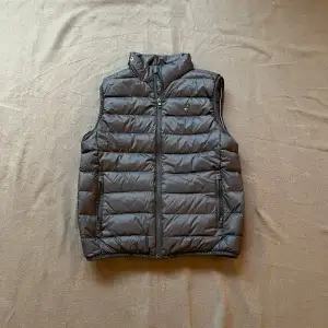 Snygg svart dunväst från Tommy Hilfiger med dragkedja framtill. Storlek 164