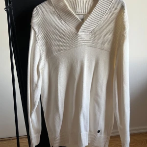 Vit stickad tröja från Jack & Jones - Säljer en stilren vit stickad tröja från Jack & Jones. Tröjan har en v-ringad design med ribbade detaljer vid krage och ärmslut. Perfekt för kyligare dagar och ger en klassisk look.
