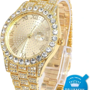 Guldfärgad klocka med strass - Snygg guldfärgad klocka från Halukakah med glittrande strass runt boetten och länken. Urtavlan har romerska siffror och en datumvisare. Perfekt för att ge en lyxig touch till din stil.