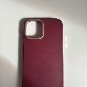 Snyggt vinrött mobilskal med guldfärgad kant runt kameran. Perfekt för att ge din telefon ett stilrent och elegant utseende. Passar bra för att skydda mot repor och stötar. iPhone 12 
