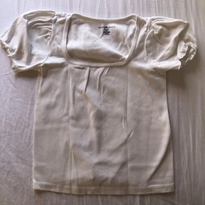 Vit topp från Brandy Melville - Säljer en söt vit topp från Brandy Melville med puffiga korta ärmar och fyrkantig halsringning. Tillverkad i 100% bomull.