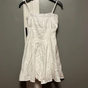 Vit klänning från NAKD - Säljer vit klänning från NAKD i storlek 36 med smala axelband som går att justera efter önskad längd (se bild 3) 💕 Klänningen har en luftig passform och är perfekt för kommande festligheter som studenten 🎓eller midsommarfirandet 🍓Vid dragkedjan har det brustit något i tyget, men detta syns knappt och går lätt att fixa. I övrigt är klänningen i ett mycket fint skick💕💖🌸