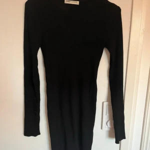 Svart ribbad klänning från Pull&Bear - Snygg svart ribbad klänning från Pull&Bear i storlek S. Klänningen har en tight passform och långa ärmar, perfekt för en stilren look. Tillverkad i ett mjukt och stretchigt material som sitter bekvämt. Använd 1 gång!🖤