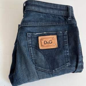 Snygga mörkblå jeans från D&G med klassisk femficksdesign och en läderpatch med logotyp på bakfickan. Perfekta för en stilren look.