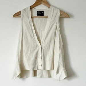 Vit v-ringad väst - Snygg vit v-ringad väst med knappar framtill. Perfekt för en stilren och enkel look. Passar bra till både vardag och festliga tillfällen.