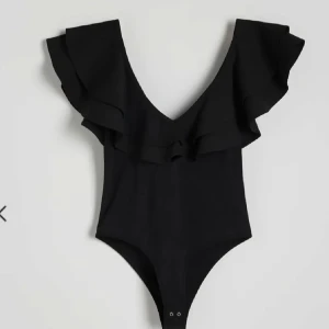 Slutsåld Svart body med volangdetaljer - Snygg svart blus med volangdetaljer och v-ringning. Perfekt för en stilren look. Storlek s💕