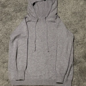Merinoull hoddie - Säljer en stilren grå hoodie med långa ärmar och justerbar huva. Perfekt för en avslappnad look. Ribbstickade muddar vid ärmslut och nederkant ger en skön passform. Inga tecken på användning!!