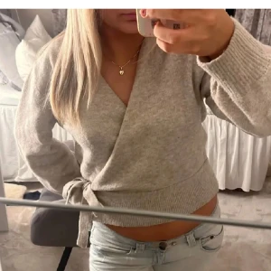 Grå knyt tröja ifrån & other stories 🩵🩵 - Säljer en mysig grå omlott tröja med knytning i sidan. Tröjan har långa ärmar och är perfekt för en avslappnad stil. Passar bra till jeans eller kjol. Den är lite nopprig. 