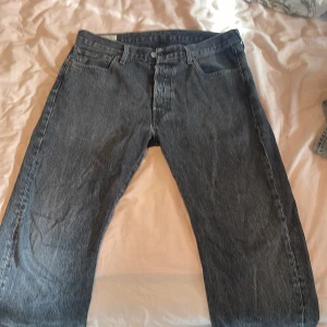 Svarta jeansbyxor från Levis - Säljer ett par klassiska blå jeans från Levis. De har en rak passform med fem fickor och knappgylf. Perfekta för en avslappnad stil. Och i jätte bra skick 