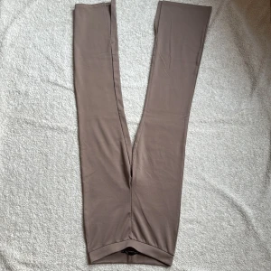 Beige leggings med slit längst ner - Säljer ett par stilrena beige leggings i mjukt material. Perfekta för en avslappnad look eller som basplagg i garderoben. De har en enkel design utan detaljer och är sköna att bära.