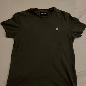 Mörkgrön t-shirt från Lyle & Scott - Säljer en stilren mörkgrön t-shirt från Lyle & Scott med korta ärmar och en liten broderad logotyp på bröstet. Perfekt för en avslappnad look.