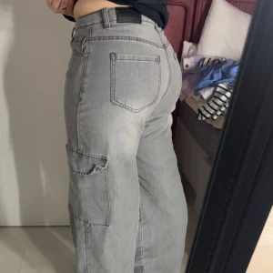 Grå cargobyxor från Boohoo - Snygga grå cargobyxor från Boohoo med hög midja och praktiska fickor på sidorna. Byxorna har en loose passform och är perfekta för en avslappnad stil. Tillverkade i ett bekvämt material som passar bra till vardags. För referens är 166cm med storlek 40/M. 