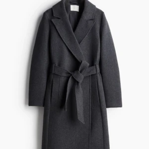 Grå kappa med bälte - Snygg grå kappa med knytbälte i midjan. Perfekt för kyligare dagar med sin stilrena design och långa ärmar. Ett måste i garderoben för en elegant look.
