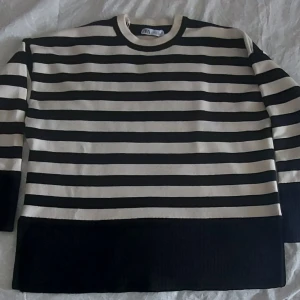 Randig tröja från Zara - Säljer en snygg randig tröja från Zara i svart och beige.. Tröjan har en normal passform med långa ärmar och är tillverkad i ett mjukt material. Perfekt för en stilren look. Helt nytt och stor passform. 