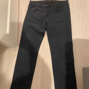 Svarta byxor från GANT - Snygga svarta byxor från GANT med dragkedja och knapp framtill. Byxorna har en klassisk design med fem fickor och bälteshällor. Perfekta för en stilren look.