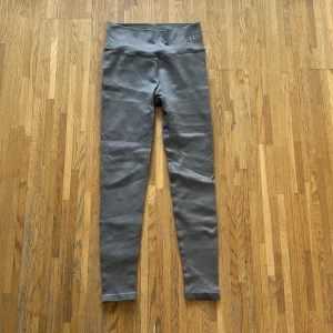 Träningstights från Stronger - Snygga beiga träningstights från Stronger med hög midja och ribbad struktur. Perfekta för träning eller en avslappnad dag. Tillverkade i en mjuk och stretchig blandning av polyamid och elastan för bästa komfort.