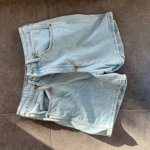 Ljusblå jeansshorts från Wrangler - Säljer ett par ljusblå jeansshorts från Wrangler. De har en klassisk femficksdesign och stängs med dragkedja och knapp. Passar s/m