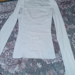 Vit ribbad tröja från H&M - Säljer en stilren vit ribbad tröja från H&M. Tröjan har en fyrkantig halsringning och långa ärmar, perfekt för en elegant look. Passar bra till både jeans och kjol.