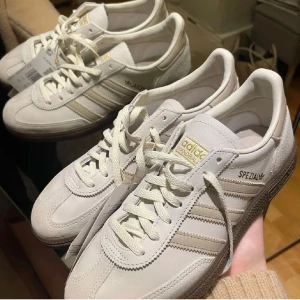 Adidas Handball Spezial W - Helt slutsålda populära skor. Ej använda bara provade. Snygga Adidas Handball Spezial W sneakers i en stilren vit färg med klassiska tre ränder på sidan. Skorna har snörning och en bekväm passform, perfekt för vardagsbruk. Tillverkade i syntetmaterial med en gummisula för bra grepp.